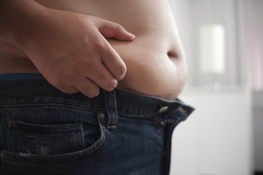 Fat bald man's belly on background of white room