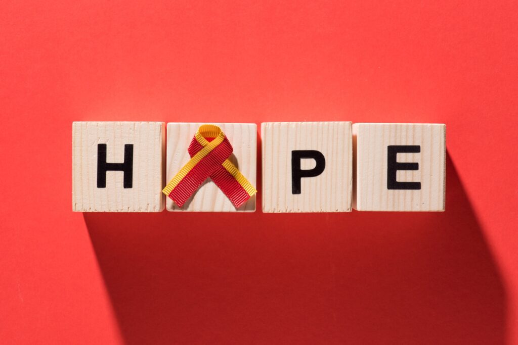 top view of ribbon and lettering hope from wooden cubes on red background, world hepatitis day